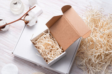 White cardboard, carton boxes with shredded filler on wooden table