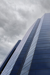 Fototapeta na wymiar Low angle partial view of a skyscraper facade under cloudy sky