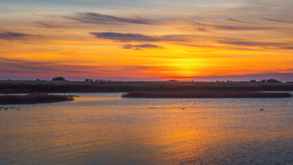 Orange sunset on a quiet lake, sunset reflected in calm water