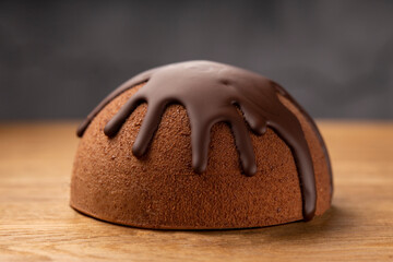 French mousse cake covered with chocolate glaze on wooden background.