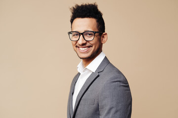 Young handsome man with wearing gray jaket, white shirt and glasses over beige background face smiling looking at the camera. Positive person, professor style