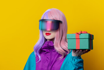 Style woman in VR glasses and 90s sport suit hold gift box on yellow background