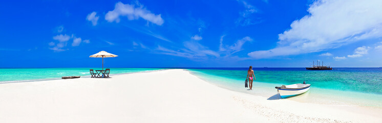 Fototapeta na wymiar Beautiful Maldives beach with parasol and bikini model snorkelling.