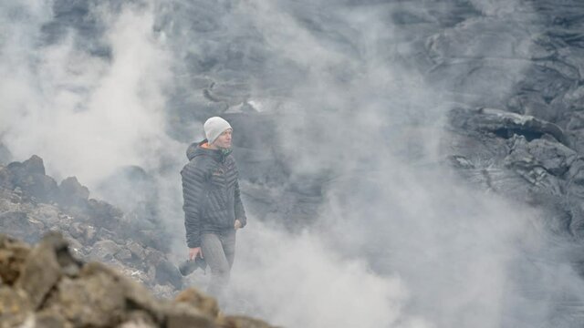 Photographer Holding Camera Amongst Smoking Lava Field