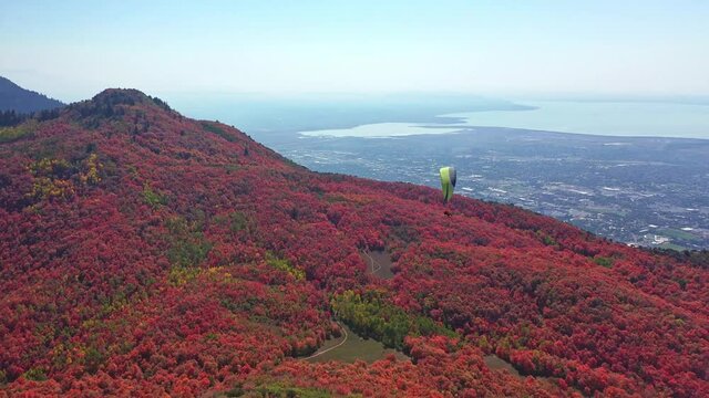 Paraglider flies over the autumn fall colors above the mountains of Utah Valley