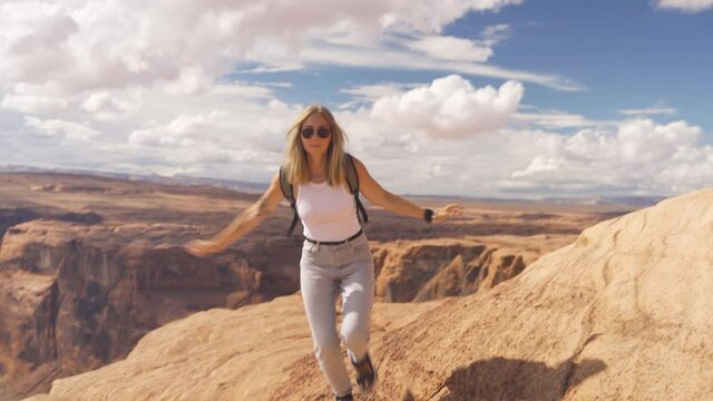 Young female adult hiker on a trail among the sandstone cliffs in Utah, USA. Cosmic landscape, adventure and travel concept.