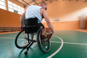 Obraz premium Close up photo of wheelchairs and handicapped war veterans playing basketball on the court