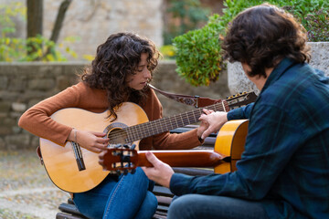 Young girl learning to play Spanish guitar in the street with a teacher