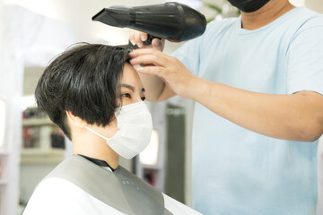 A beautiful asian woman with face covering happy getting haircut at a salons during Covid 19 pandemic. New normal, Face mask required, Bob, Pixie cut, Leisure, Lifestyle, Professional, Satisfied.