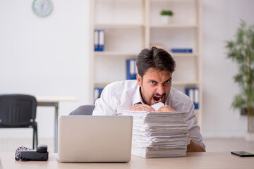 Fototapeta premium Young male employee and too much work in the office