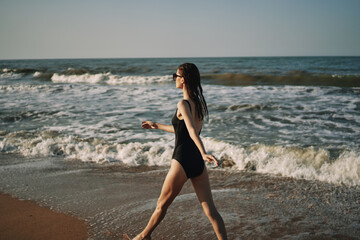 woman in black swimsuit walking on the beach ocean summer