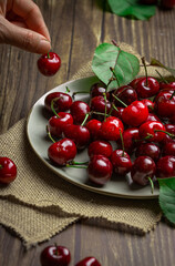 A plate of red cherries on linen napkin and  wooden table .
