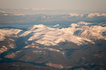 Obraz premium Snowy Rocky Mountains peaks at Sunrise from an airplane