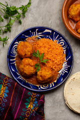 meatballs with red rice and tomato broth on a gray background. Mexican food