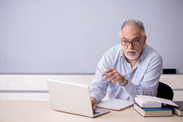 Old male teacher in front of whiteboard