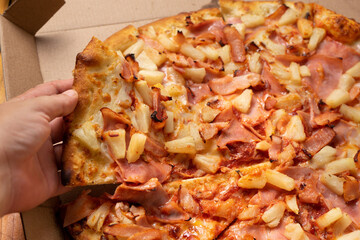 Ham and pineapple pizza called hawaiian on a wooden background
