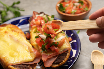 Molletes with ham, refried beans and melted cheese on a gray background. Mexican food