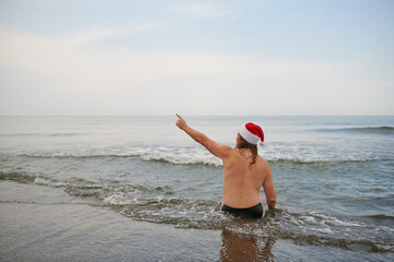 a man wearing a santa claus hat at the sea