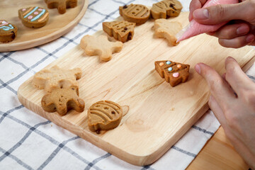 Bakery man decorating Christmas cookies with colorful icing sugar, homemade ginger bread cookies, making Xmas gingerbread cookie, preparing bakery, process of baking and cooking at home