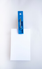 Pinza azul de pl&aacute;stico agarrando un papel blanco limpio para montaje