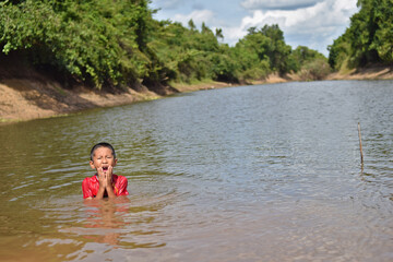 happy asian boy playing water in river