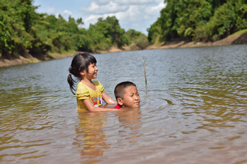 boy and girl playing water in the river