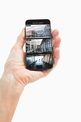 Hand of caucasian man holding smartphone with views of offices from security cameras on screen