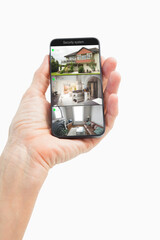 Hand of caucasian man holding smartphone with view of home from security cameras on screen