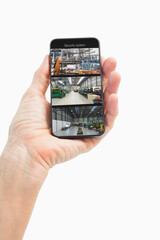 Hand of caucasian man holding smartphone with view of warehouse from security cameras on screen