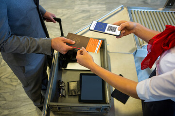Man at airport showing documents and smartphone with covid 19 vaccine passport at check in