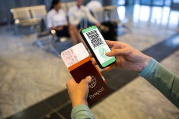 Woman at airport holding documents and smartphone with covid 19 vaccine passport at check in