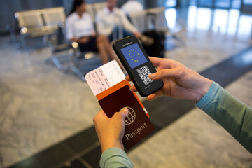 Woman at airport holding documents and smartphone with covid 19 vaccine passport at check in