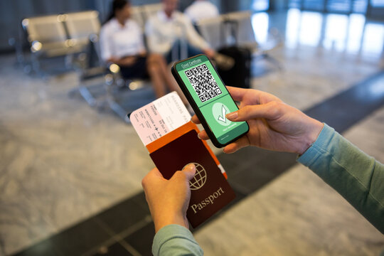 Woman At Airport Holding Documents And Smartphone With Covid 19 Vaccine Passport At Check In