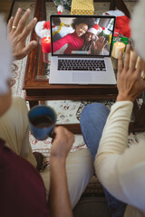 Two waving men making laptop christmas video call with smiling african american mother and daughter