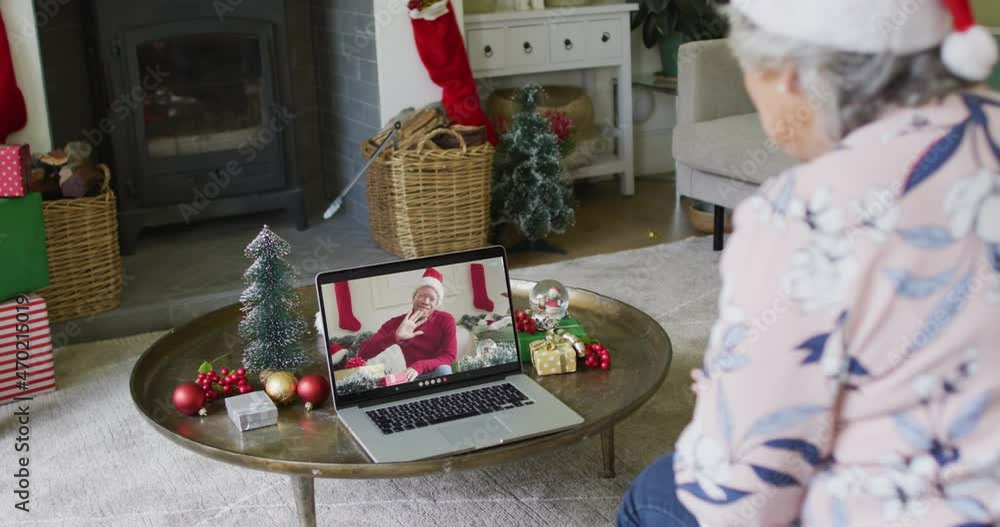 Canvas Prints Caucasian senior woman with santa hat using laptop for christmas video call with man on screen