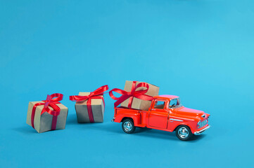 red vintage pickup truck car is carrying a gift box gifts with a red bow gift on a blue background.