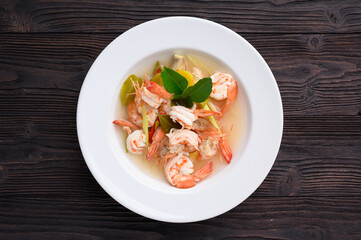 Tom Yum Goong Clear Spicy Sour Soup on wooden table top view, Thai local food