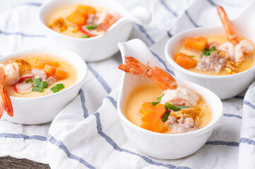 Homemade style steamed egg with shrimp and vegetables in a ceramic bowl on wooden table. healthy food concept.