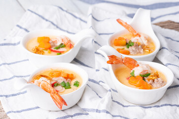 Homemade style steamed egg with shrimp and vegetables in a ceramic bowl on wooden table. healthy food concept.