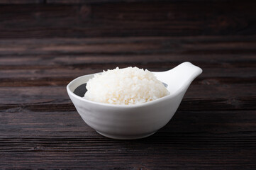 Bowl of boiled rice served on wooden table,