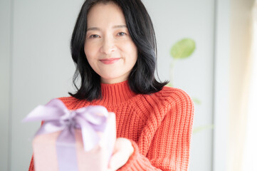 Beautiful Asian (Japanese) woman offering a gift Close-up, looking at camera, copy space