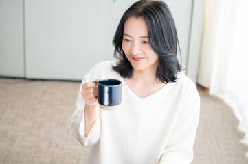 コーヒーを飲みながらくつろぐアジア人（日本人）女性　コピースペースあり　正面