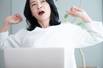 仕事の休憩中にあくびをする美しいアラフォーのアジア人(日本人女性)  ...