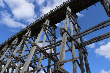 old timber railway trestle bridge in a blue sky with clouds
