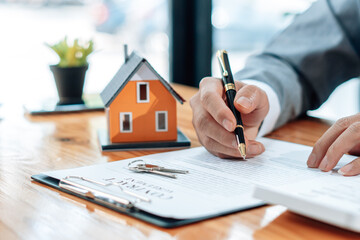 Customers interested in buying a home sign a signature to enter into a home purchase contract with a real estate agent. Mortgage loan approval home loan and insurance concept.