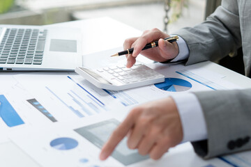 Businessman pen pointing graph chart in this month and use calculator for Plans to improve quality...