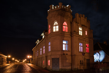 House with a tower with lights on the windows in different colors. Day of proclamation of the Republic of Latvia