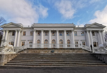 The entrance to the Elaginoostrovsky Palace with a staircase and white lions against a blue sky with clouds