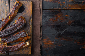Grilled pork ribs with rosemary and honey, on wooden serving board, on old dark  wooden table background, top view flat lay, with copy space for text