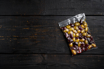 Olives in vacuum packaging for supermarket, on black wooden table background, top view flat lay,...